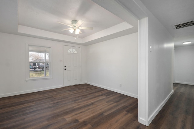 entryway featuring visible vents, dark wood-type flooring, baseboards, a raised ceiling, and ceiling fan