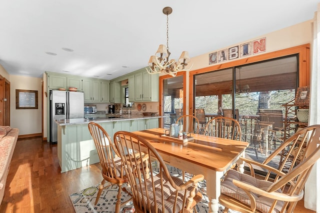 dining space featuring a chandelier, dark wood finished floors, and baseboards