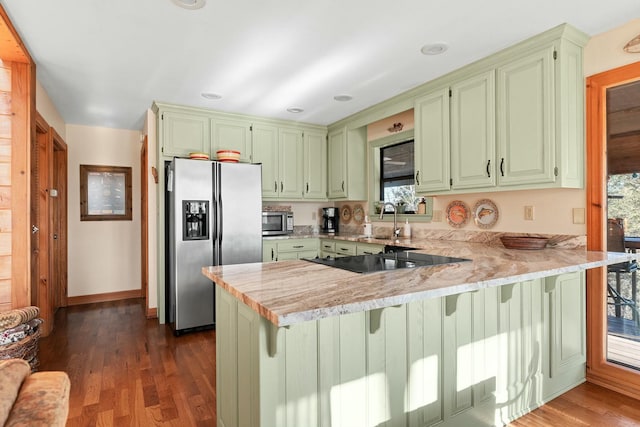 kitchen featuring green cabinetry, a peninsula, a sink, stainless steel appliances, and dark wood-type flooring