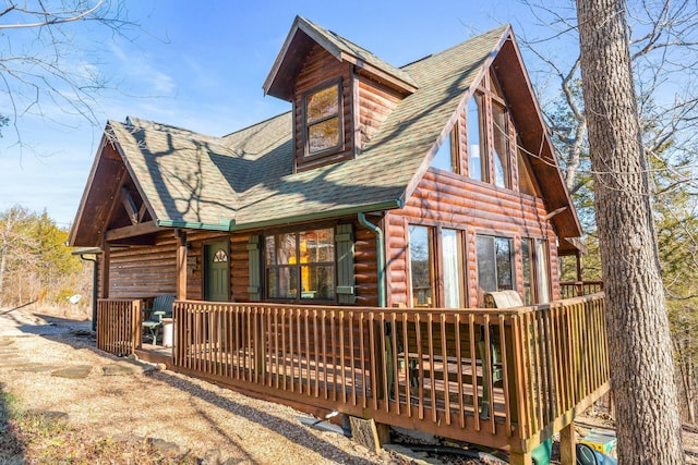 back of house featuring log veneer siding and roof with shingles