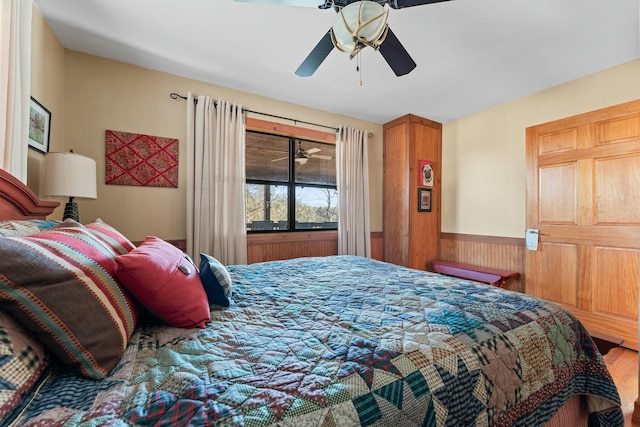 bedroom with a wainscoted wall and ceiling fan