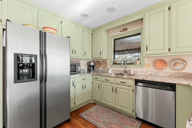 kitchen featuring a sink, light stone countertops, appliances with stainless steel finishes, and dark wood-style floors