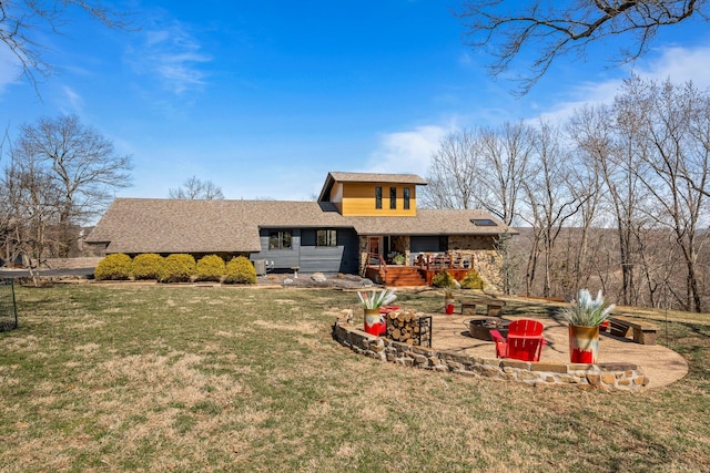 view of front facade featuring a shingled roof, a front yard, a deck, and an outdoor fire pit