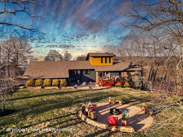 back of property featuring a lawn, driveway, an outdoor fire pit, and a patio