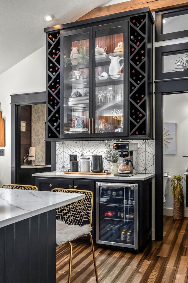 bar featuring wine cooler, vaulted ceiling, a dry bar, and wood finished floors