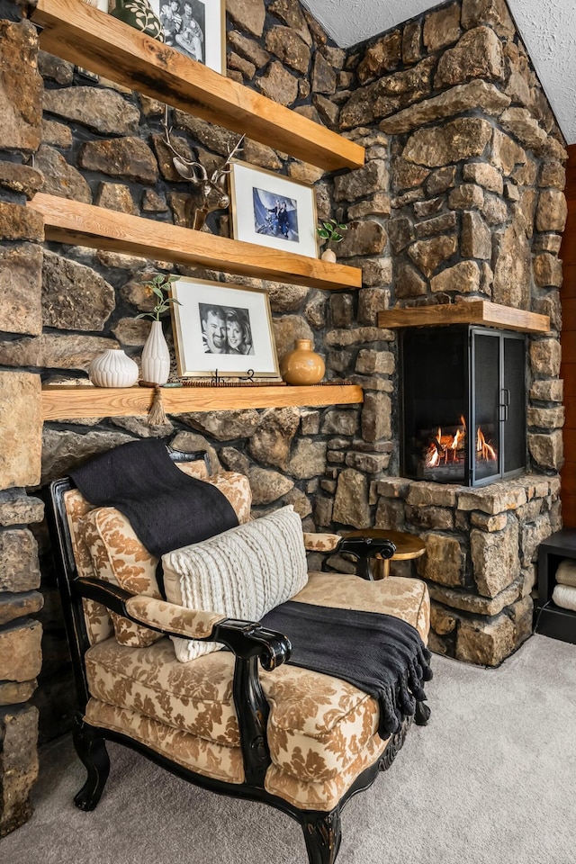 carpeted living area featuring a fireplace, a textured ceiling, and lofted ceiling