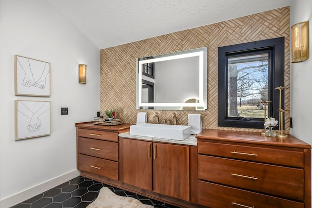 bathroom with lofted ceiling, a textured ceiling, tile patterned flooring, baseboards, and vanity