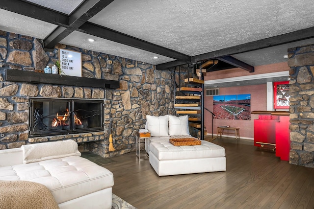 living area with beamed ceiling, visible vents, wood-type flooring, and a textured ceiling