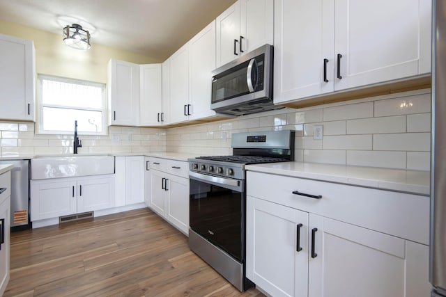 1883 S Farm Rd Unit 107, Springfield, MO 65802 - kitchen featuring appliances with stainless steel finishes, a sink, light countertops, white cabinets, and decorative backsplash