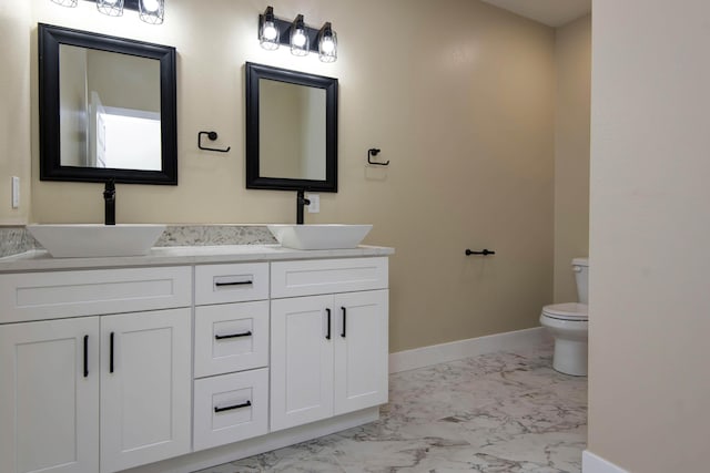 1883 S Farm Rd Unit 107, Springfield, MO 65802 - full bathroom featuring marble look tiles, toilet, double vanity, and baseboards