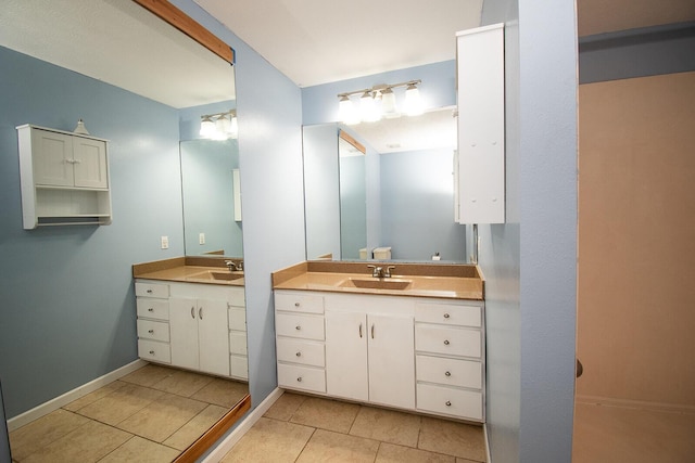 full bath featuring a sink, baseboards, two vanities, and tile patterned flooring