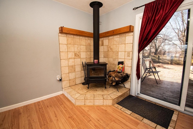 interior details with a wood stove, wood finished floors, and baseboards