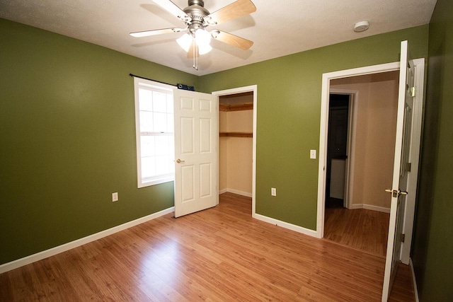 unfurnished bedroom with light wood-style flooring, a ceiling fan, baseboards, and a closet