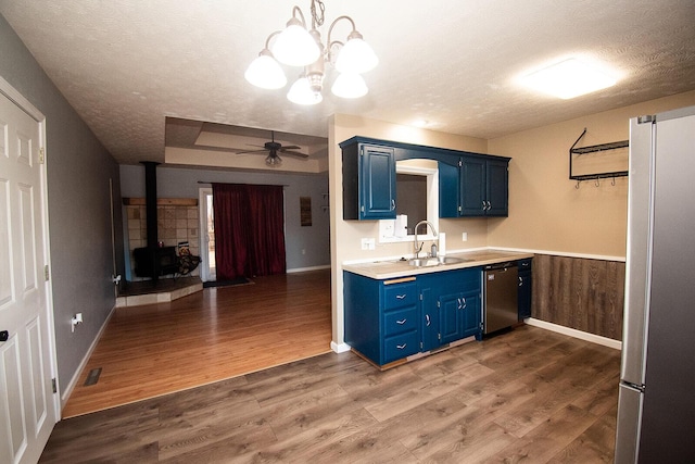 kitchen with a sink, blue cabinets, appliances with stainless steel finishes, and a textured ceiling