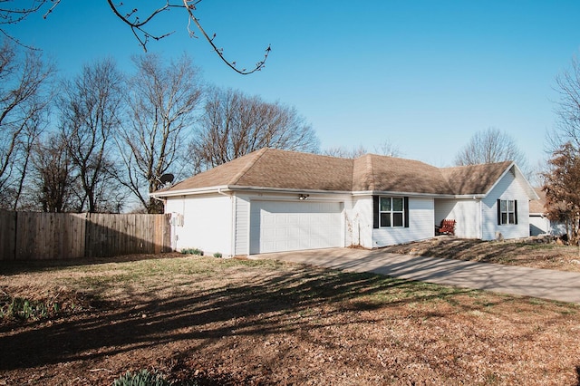 view of property exterior with driveway, an attached garage, and fence