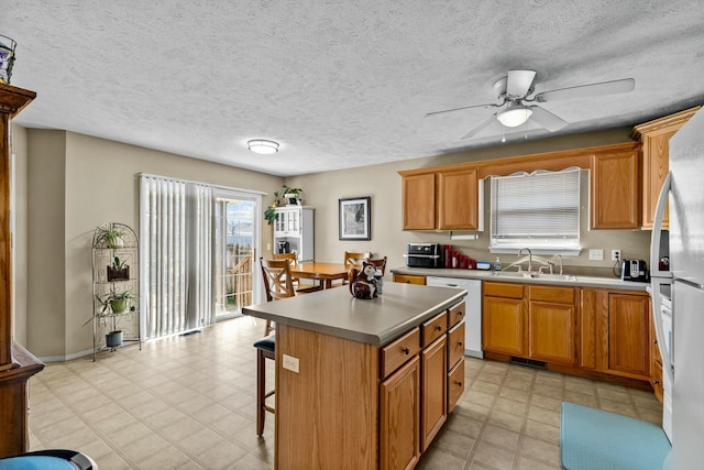 kitchen with a kitchen island, ceiling fan, a breakfast bar area, white appliances, and a sink