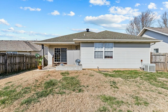 rear view of property featuring a patio, a yard, a fenced backyard, a shingled roof, and central air condition unit