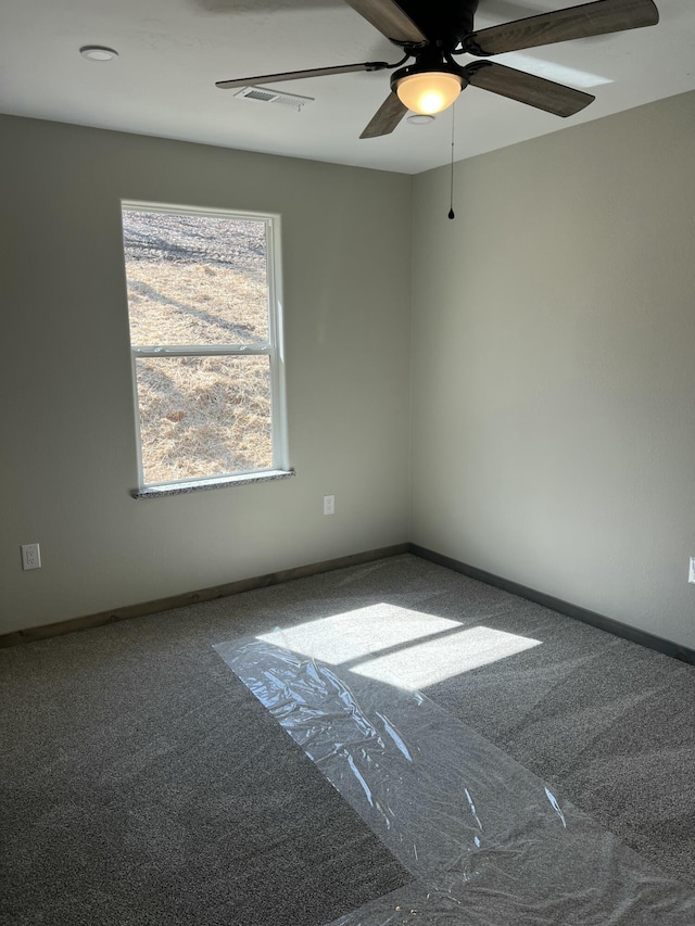 empty room featuring carpet, visible vents, a ceiling fan, and baseboards