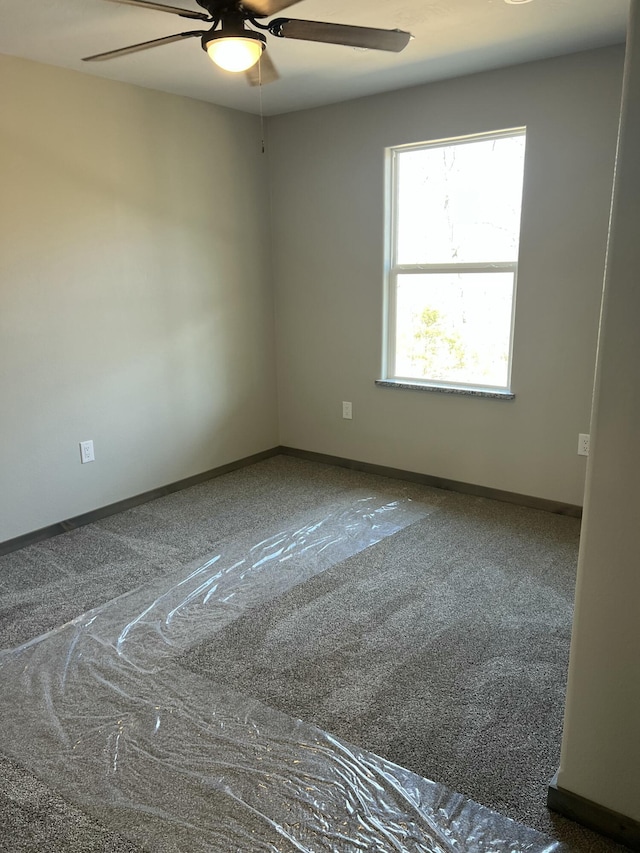 spare room with carpet, a ceiling fan, and baseboards