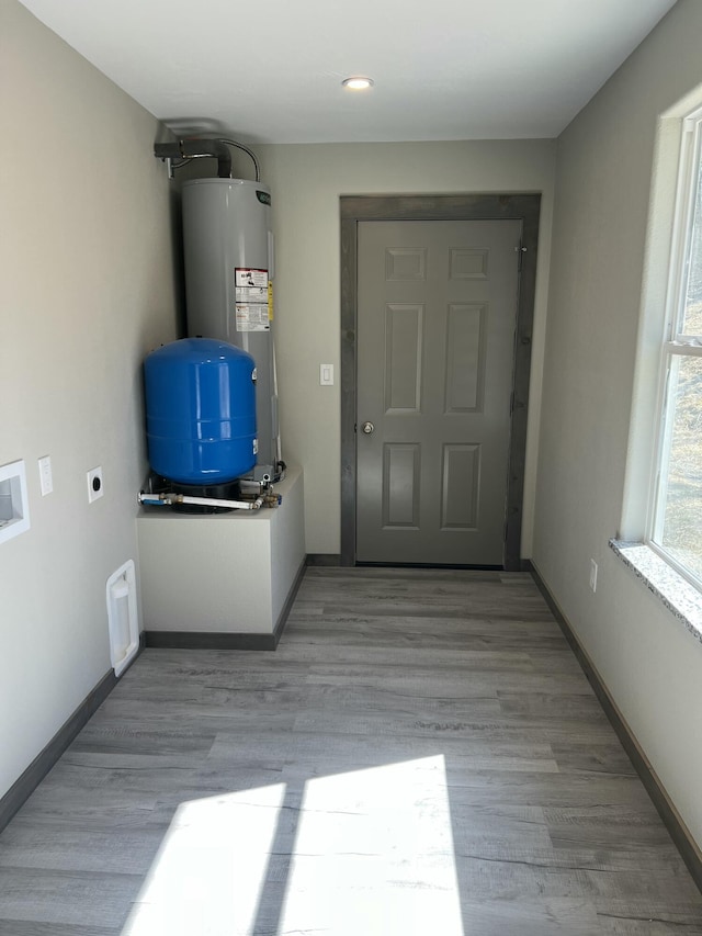 interior space featuring water heater, baseboards, and wood finished floors