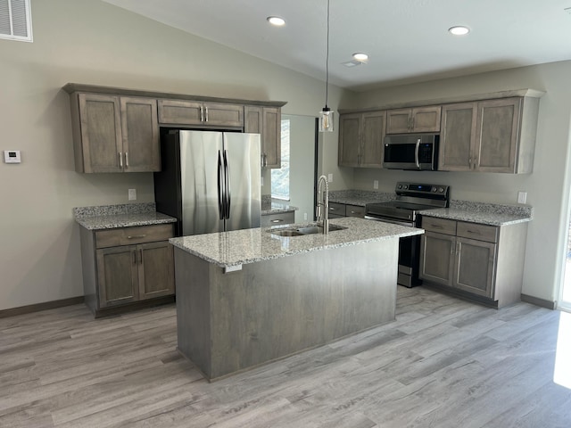 kitchen with visible vents, a sink, appliances with stainless steel finishes, lofted ceiling, and light stone countertops