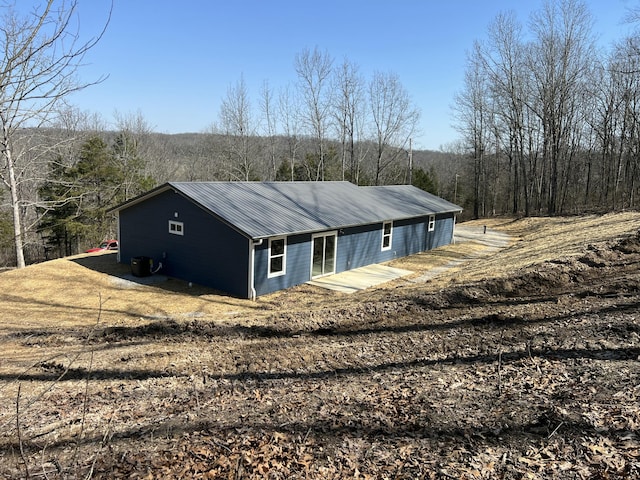 view of side of property with a wooded view and metal roof