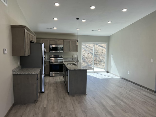 kitchen featuring a sink, light wood-style floors, appliances with stainless steel finishes, baseboards, and light stone countertops