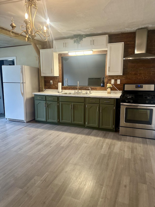 kitchen featuring stainless steel range with gas cooktop, freestanding refrigerator, a sink, extractor fan, and green cabinets