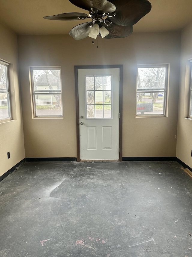 interior space featuring a healthy amount of sunlight, concrete flooring, baseboards, and ceiling fan