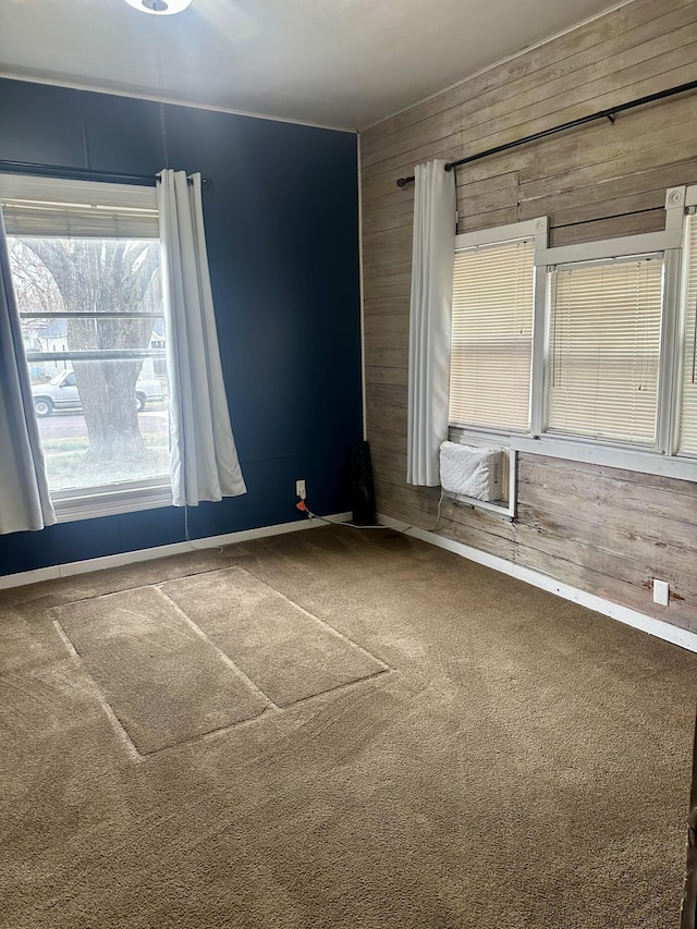 empty room featuring cooling unit, baseboards, carpet floors, and wood walls