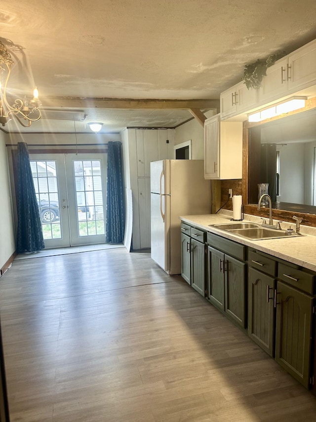 kitchen featuring wood finished floors, freestanding refrigerator, a sink, french doors, and a chandelier