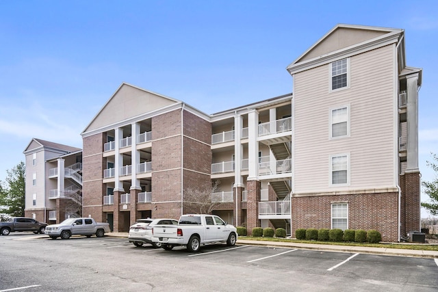 view of building exterior with uncovered parking and central AC