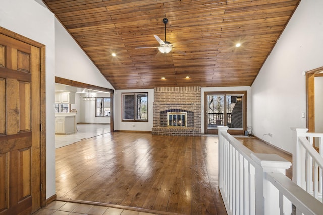 unfurnished living room featuring wooden ceiling, a fireplace, wood finished floors, high vaulted ceiling, and a ceiling fan