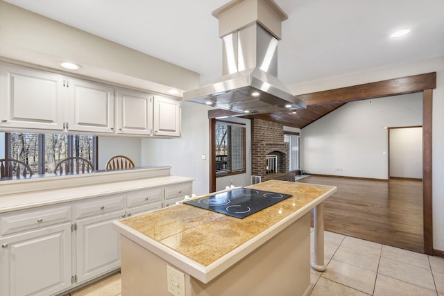 kitchen featuring island exhaust hood, a center island, white cabinets, light tile patterned floors, and black electric cooktop