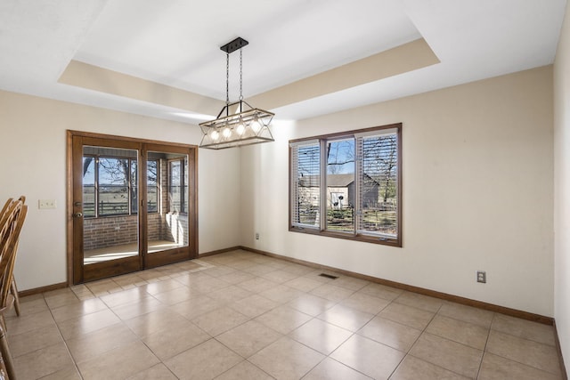 unfurnished dining area with a raised ceiling, light tile patterned floors, visible vents, and baseboards