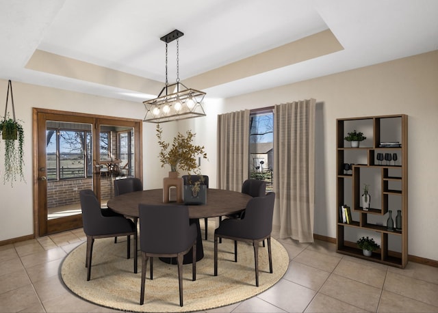 dining space with a tray ceiling, light tile patterned floors, and a healthy amount of sunlight