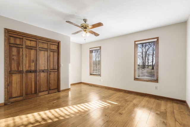 unfurnished bedroom featuring a ceiling fan, light wood-type flooring, and baseboards