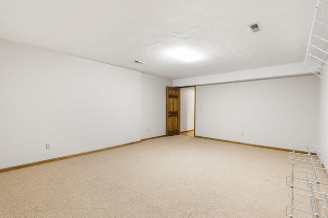 empty room featuring visible vents, light carpet, a textured ceiling, and baseboards