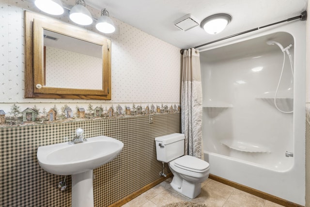 full bathroom featuring toilet, shower / bath combination with curtain, wallpapered walls, wainscoting, and tile patterned flooring