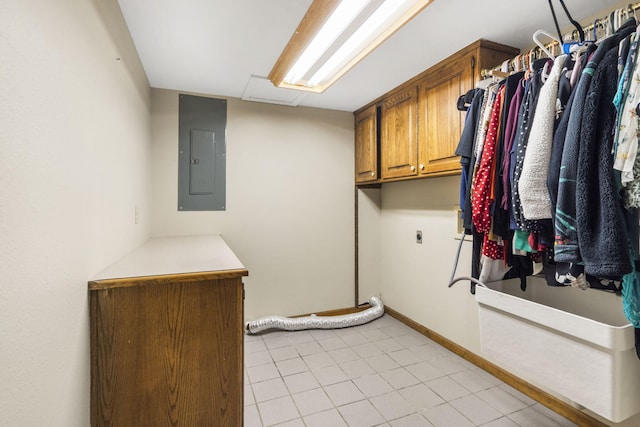 laundry room featuring baseboards, electric panel, light tile patterned floors, cabinet space, and electric dryer hookup