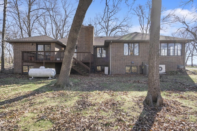 rear view of house with stairs, a wooden deck, brick siding, and a chimney