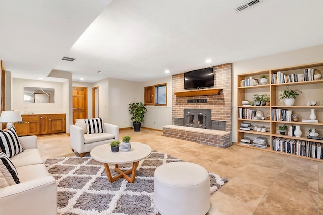 living area with recessed lighting, visible vents, baseboards, and a brick fireplace