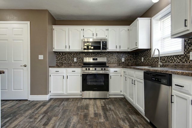 kitchen with decorative backsplash, white cabinets, stainless steel appliances, and dark wood-type flooring