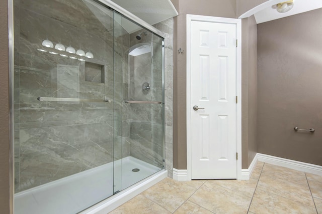 full bathroom featuring tile patterned floors, baseboards, and a stall shower