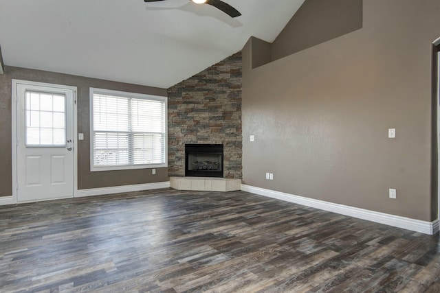 unfurnished living room with baseboards, dark wood finished floors, a stone fireplace, high vaulted ceiling, and a ceiling fan