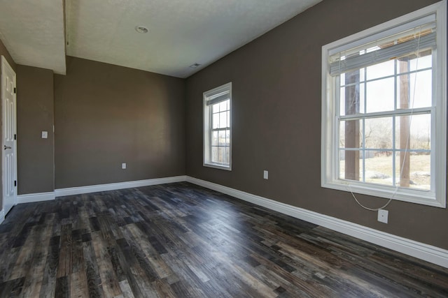 spare room with dark wood finished floors and baseboards