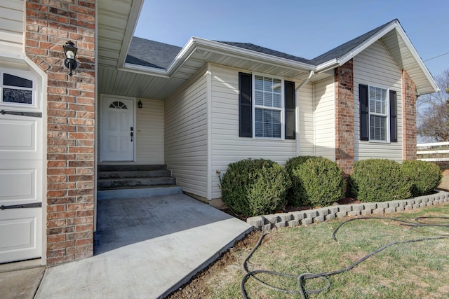 entrance to property with a garage and roof with shingles