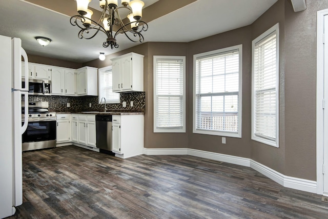 kitchen featuring dark countertops, decorative backsplash, an inviting chandelier, dark wood-style floors, and stainless steel appliances