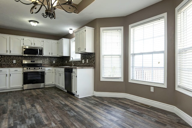 kitchen featuring decorative backsplash, dark countertops, appliances with stainless steel finishes, and a sink