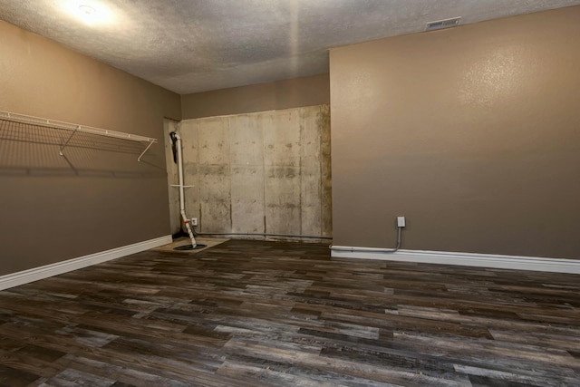 unfurnished room featuring dark wood finished floors, visible vents, a textured ceiling, and baseboards